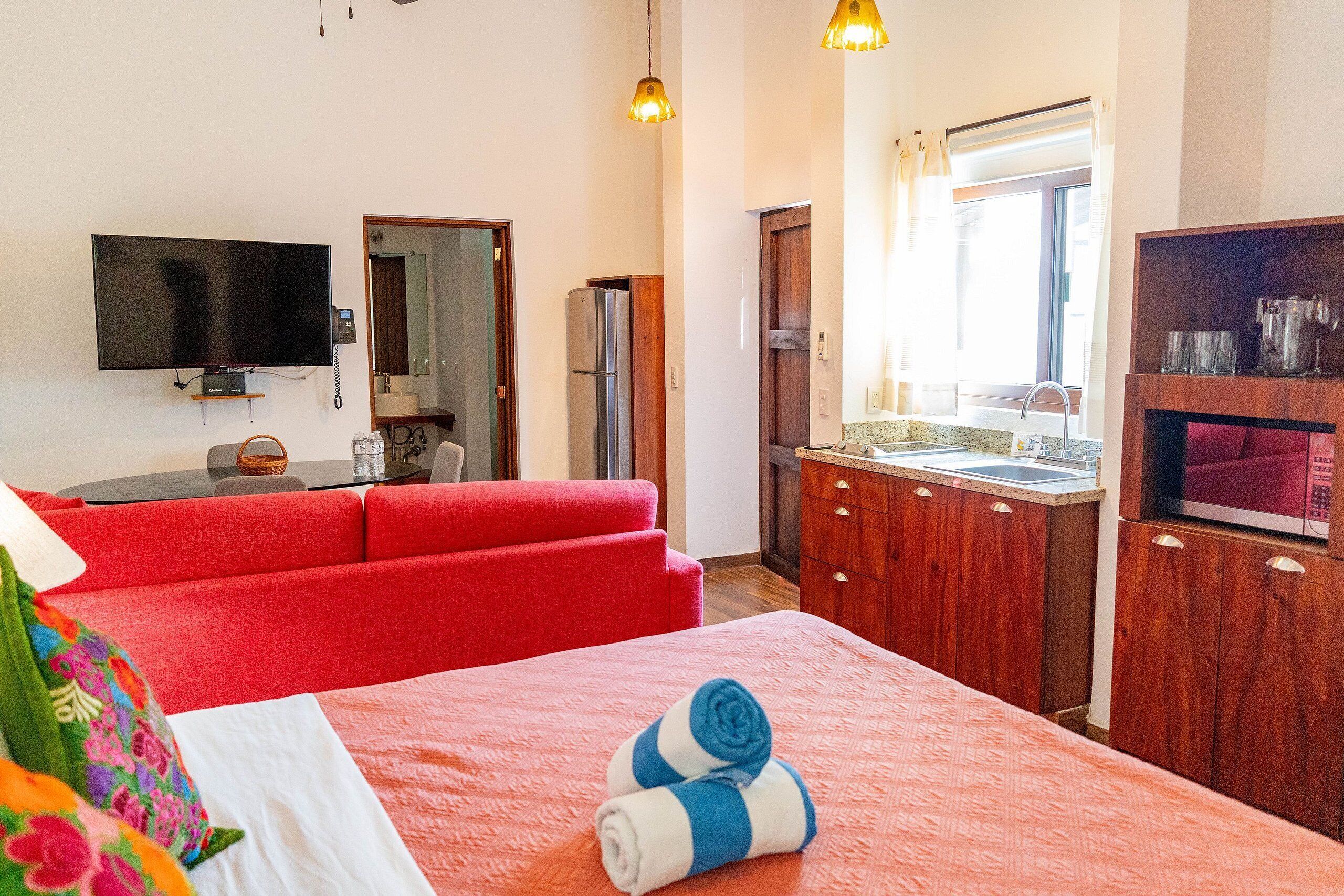 A hotel room with a large bed, a TV, a refrigerator, a wooden cabinet, and a window with curtains.