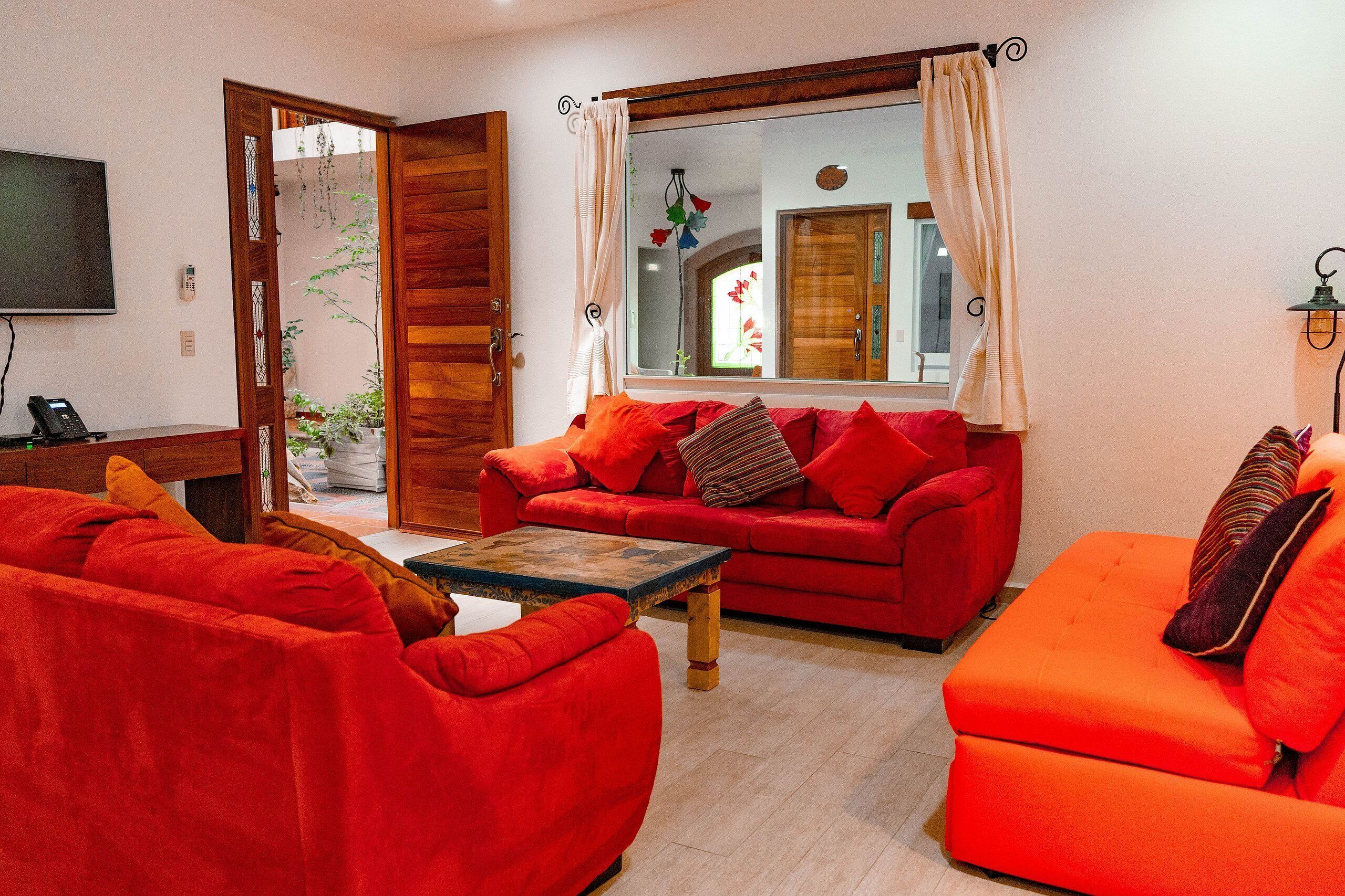 Una sala de estar con un sofá rojo, un sofá naranja y una mesa de centro de madera.