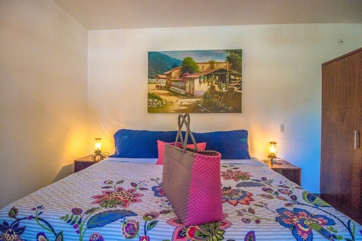 Ein Schlafzimmer mit einem Bett, einem Bild an der Wand und zwei Nachttischlampen.