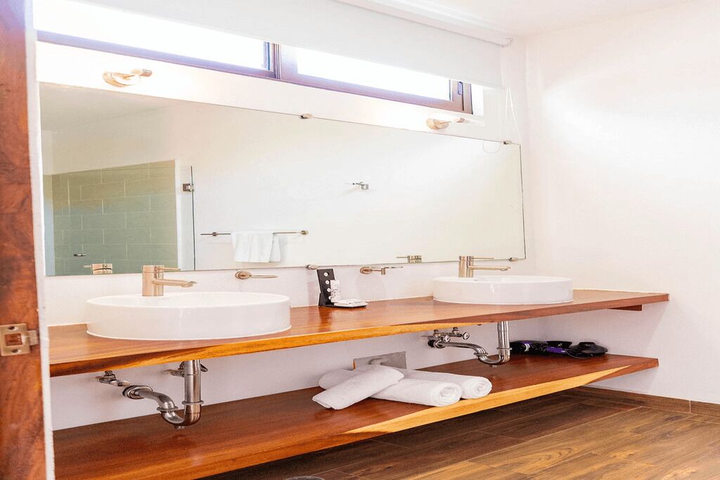 A bathroom with two sinks, a large mirror, wooden shelves, and a towel rack.