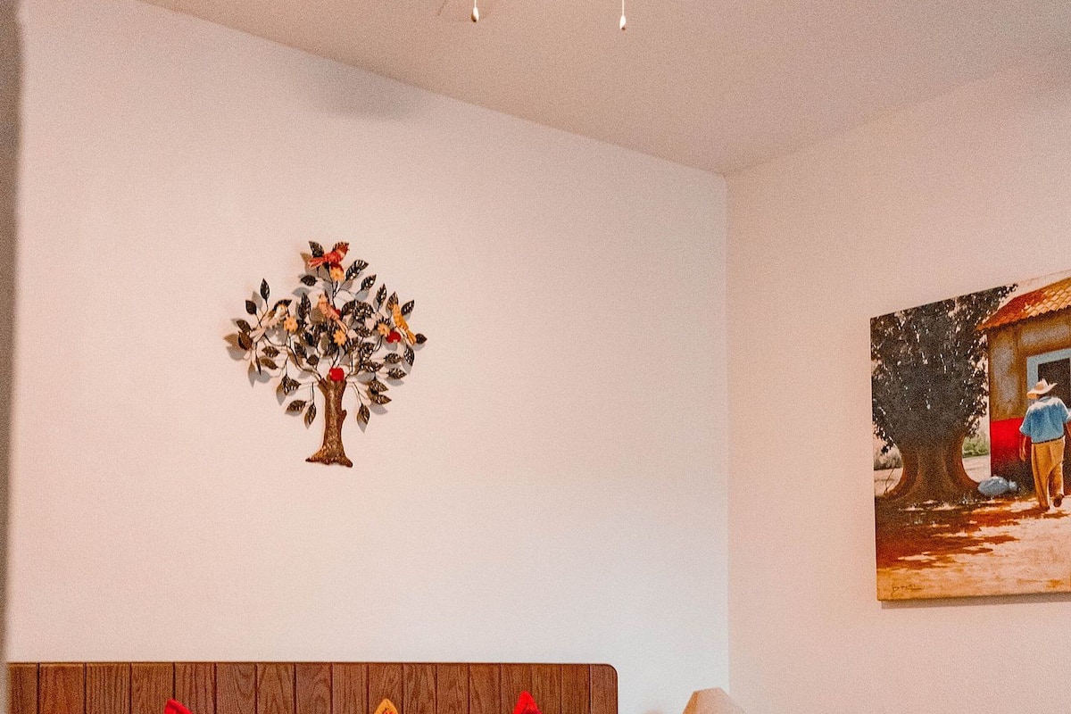 Ein Schlafzimmer mit einem Holzkopfteil, einer roten Bettdecke und einem Deckenventilator.