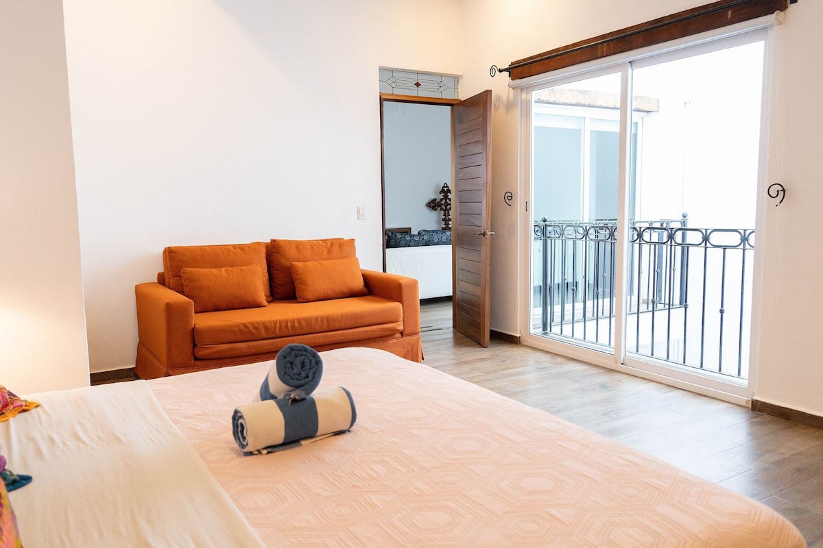 Ein Schlafzimmer mit Bett, einer Couch und einem Balkon mit Geländer.