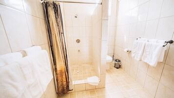 Een badkamer met een douche, toilet en handdoekrek.