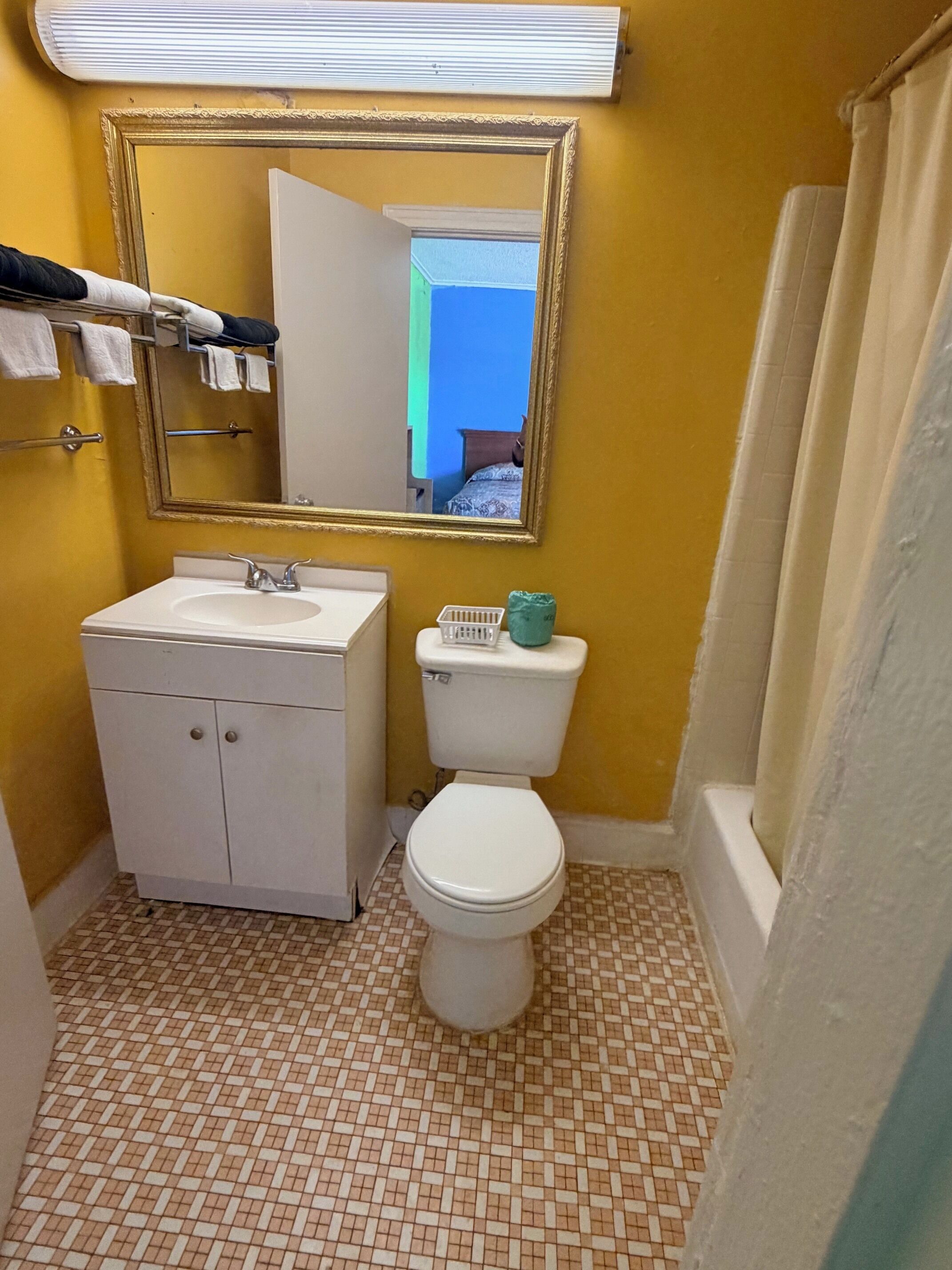 Un baño con lavamanos blanco, inodoro y espejo con marco dorado.