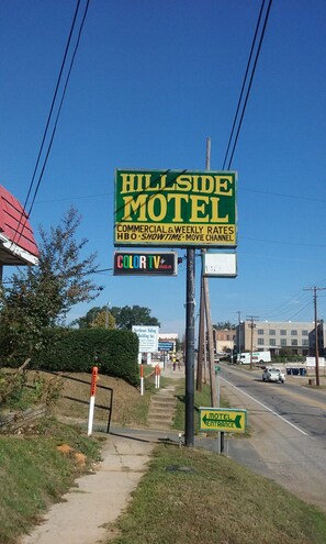 A roadside sign for Hillside Motel advertising commercial and weekly rates, HBO, Showtime, and movie channel. - Hillside Motel (Homer)