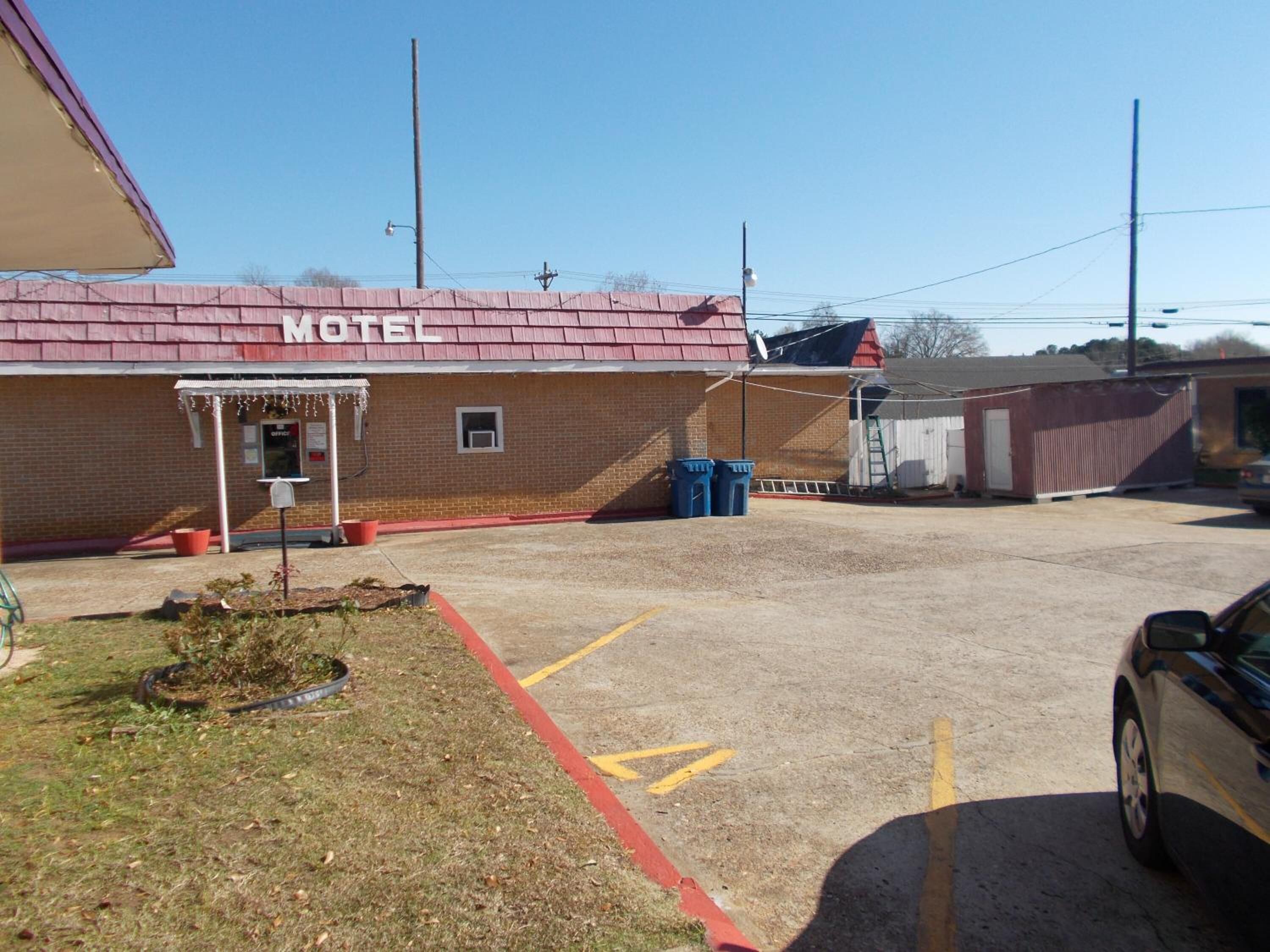 A motel with a red roof and a small porch area.