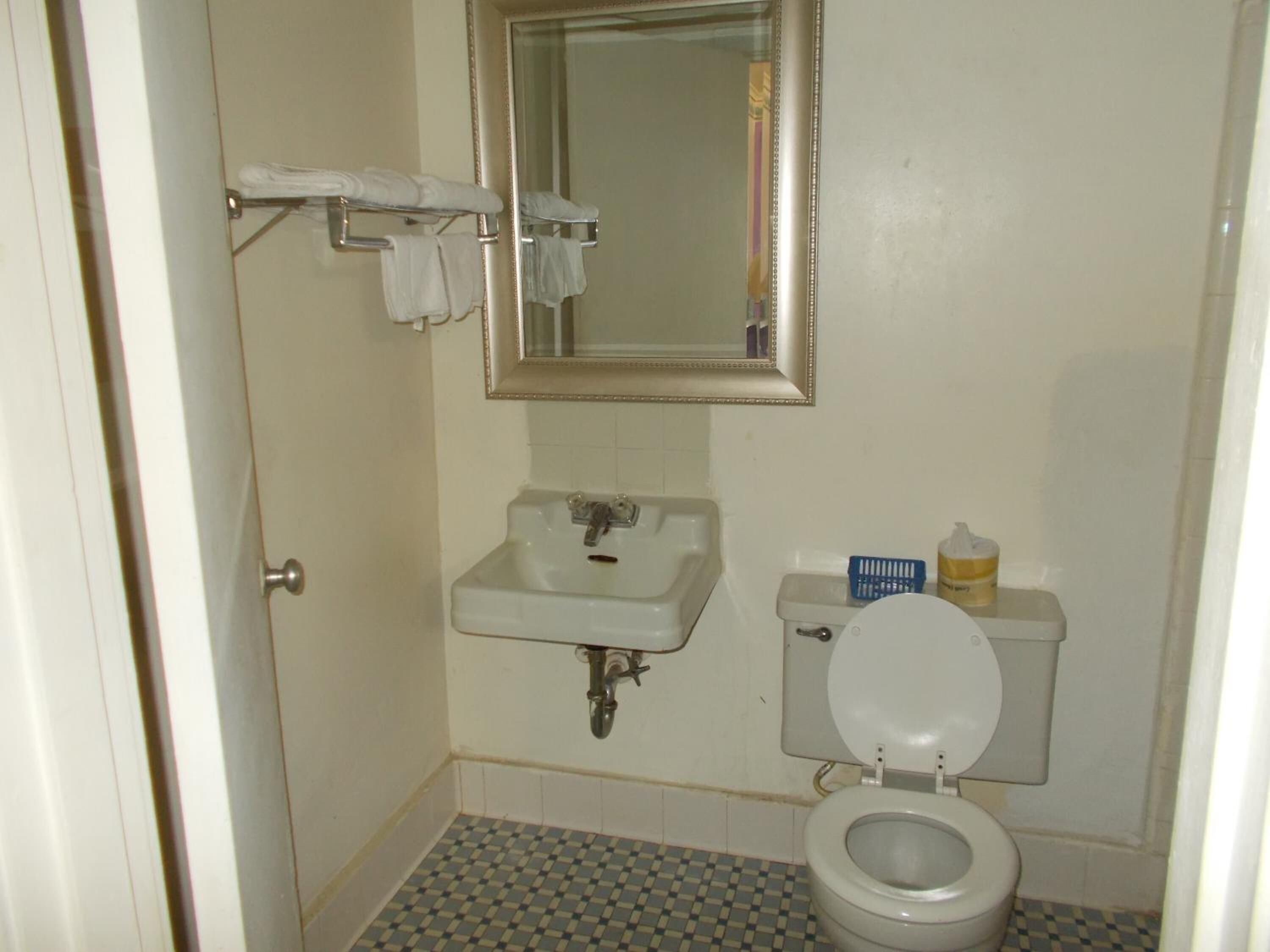 Une petite salle de bain avec un lavabo blanc, un miroir et des toilettes.