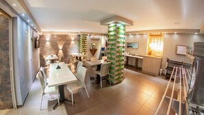 A modern kitchen with a central island, a dining area with white chairs, and a built-in TV. - Hotel Roosevelt Plaza (Cali)