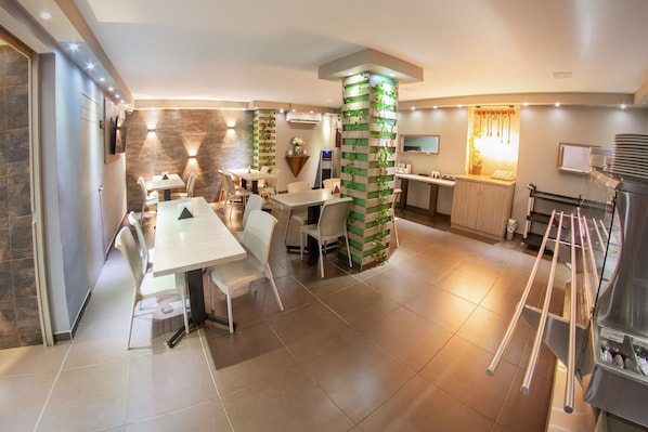 A modern kitchen with a central island, a dining area with white chairs, and a built-in TV. - Hotel Roosevelt Plaza (Cali)