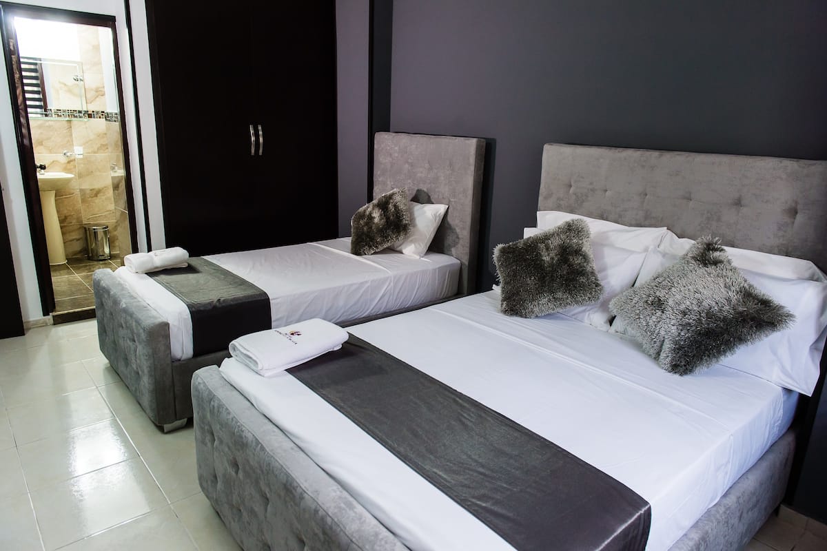 A hotel room with two beds, a bathroom visible through an open door, and a small trash bin.
