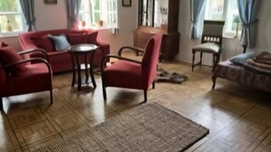 A living room with a sofa, armchairs, a small table, and a cabinet.