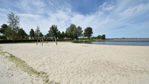 A sandy beach with a swing set and a body of water in the background.