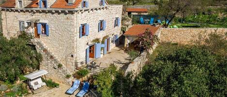 A stone villa with a swimming pool, outdoor seating, and a view of the surrounding landscape.