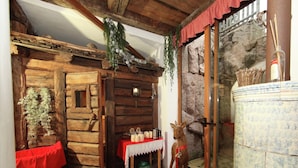 Um quarto rústico de madeira com parede de pedra, porta de vidro e uma pequena mesa com velas.