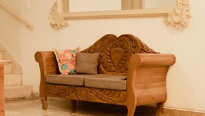 A wooden sofa with intricate carvings, positioned against a wall with a decorative molding. - Hotel Casa Guivá (Oaxaca)