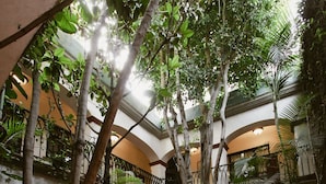A multi-level atrium with a tiled floor, multiple balconies, and various indoor plants. - Hotel Casa Guivá (Oaxaca)
