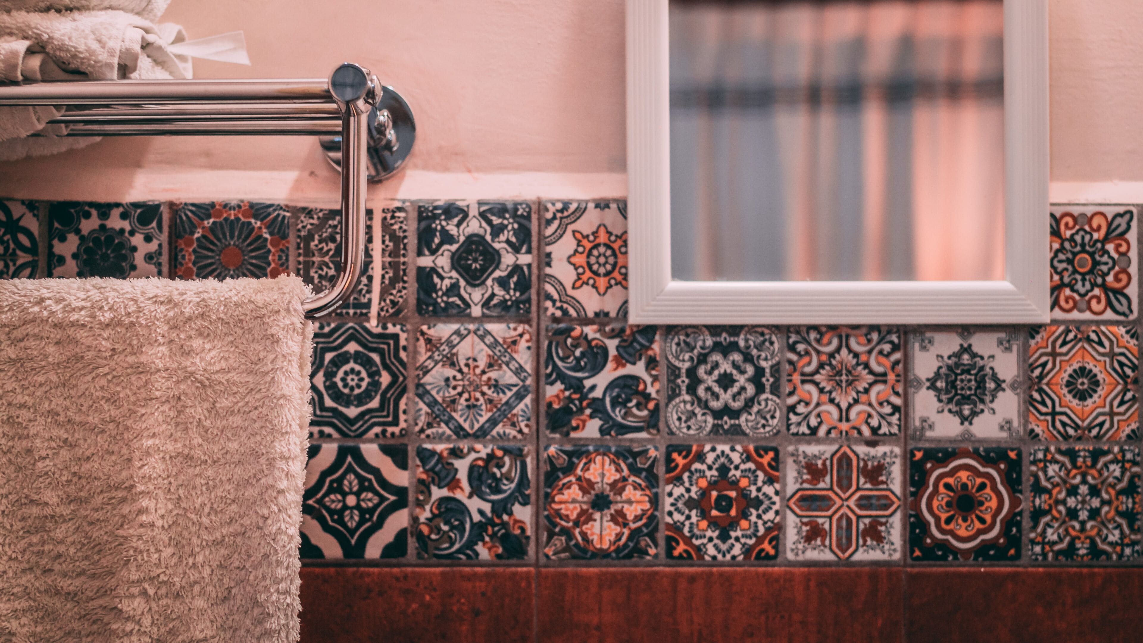 A bathroom with a towel rack, patterned tiles, and a window.