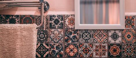 A bathroom with a towel rack, patterned tiles, and a window.
