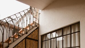 A bathroom with a large bathtub, a window with curtains, and a staircase with a bamboo wall. - Hotel Casa Guivá (Oaxaca)