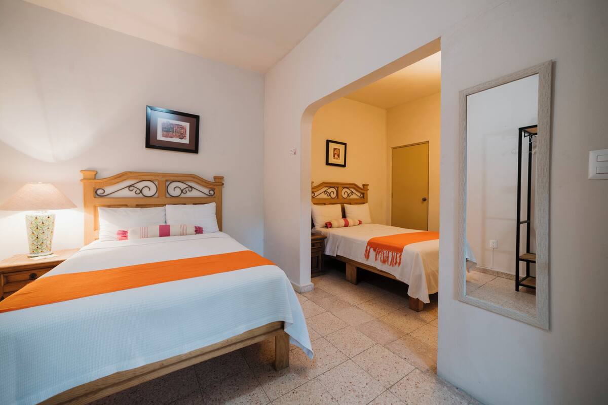 A hotel room with two beds, a large mirror, and a framed picture on the wall.