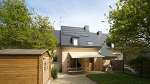 A house with a gravel driveway, a wooden shed, and a covered patio area. - Cozy Garden Home in Erquy (Erquy)