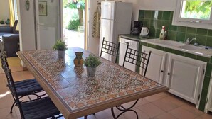 A kitchen with a tiled backsplash, a dining table with chairs, and a refrigerator. - Holiday Home in Villecroze with Pool & Garden (Villecroze)