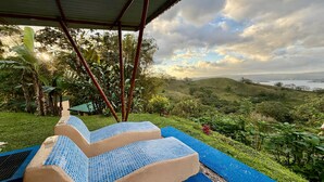 A covered outdoor seating area with a view of a lake and hills.