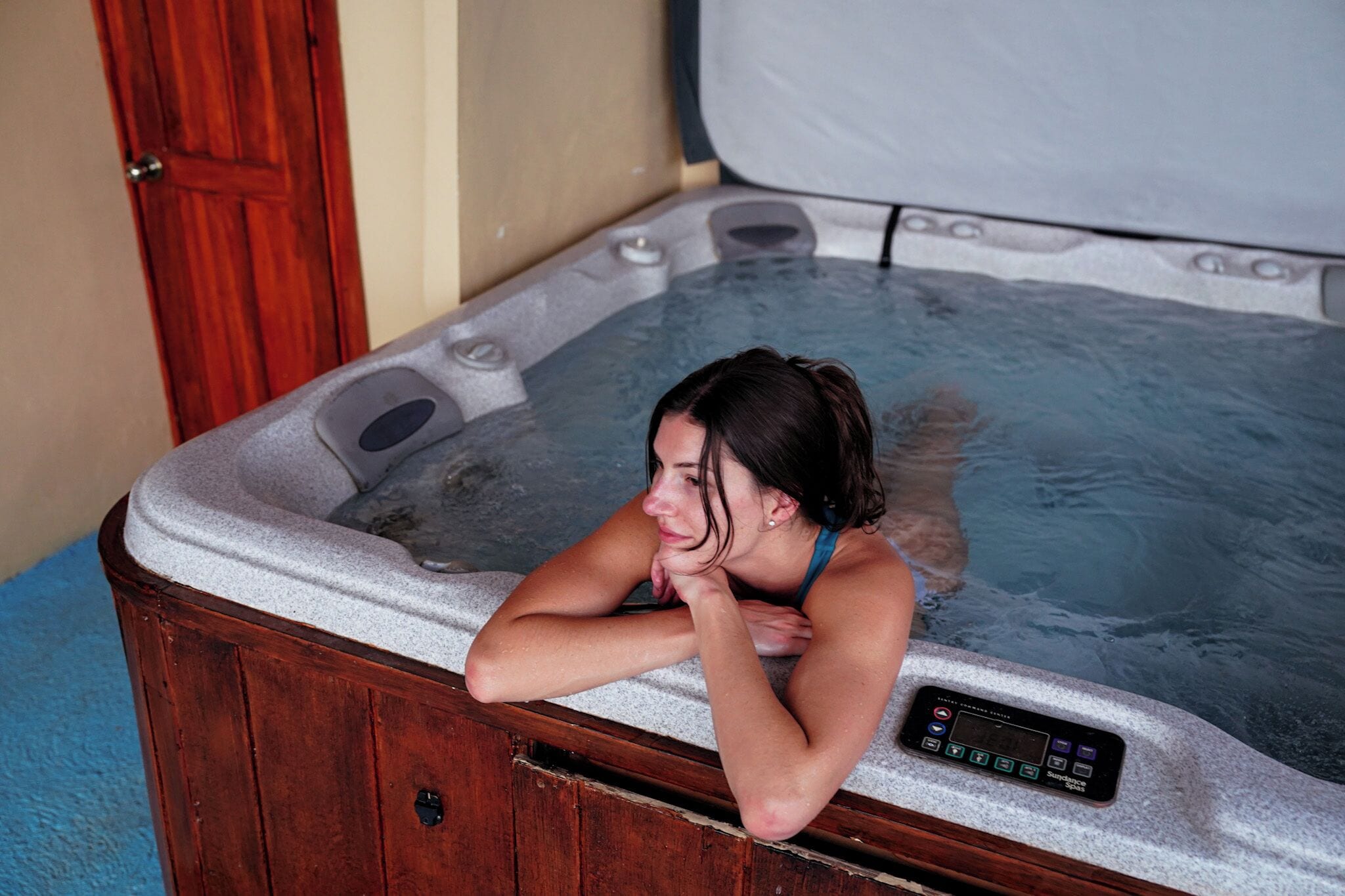 A person relaxing in a hot tub with a control panel.