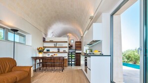 Eine moderne Küche mit Kochinsel, Holzboden und Essbereich mit braunem Ledersofa.