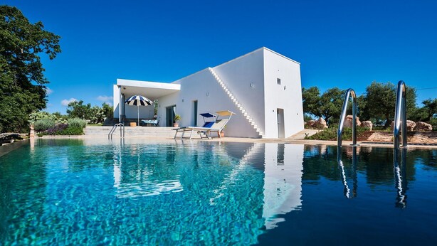 Ein modernes Haus mit Schwimmbad, Sonnenterrasse und einer Treppe, die zum Haus führt.