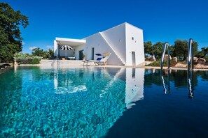 Uma casa moderna com piscina, terraço solar e escadaria que dá acesso à casa.