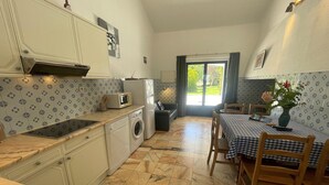 Een compact keuken met een wasmachine, magnetron en een eethoek met een geruit tafelkleed.