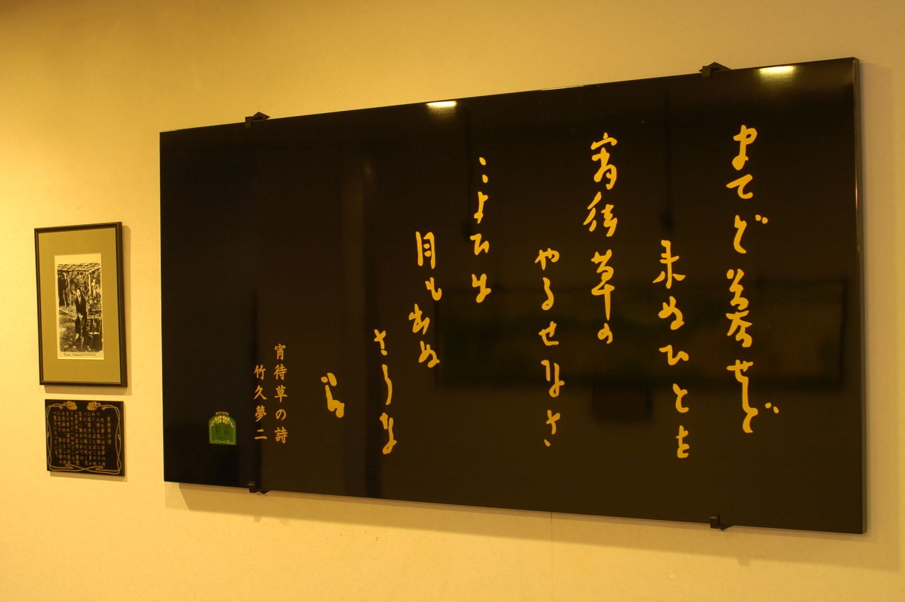 Una lavagna con calligrafia giapponese e due quadri appesi al muro.