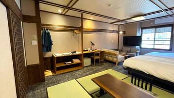 A hotel room with a bed, a desk, a chair, a TV, and a window.