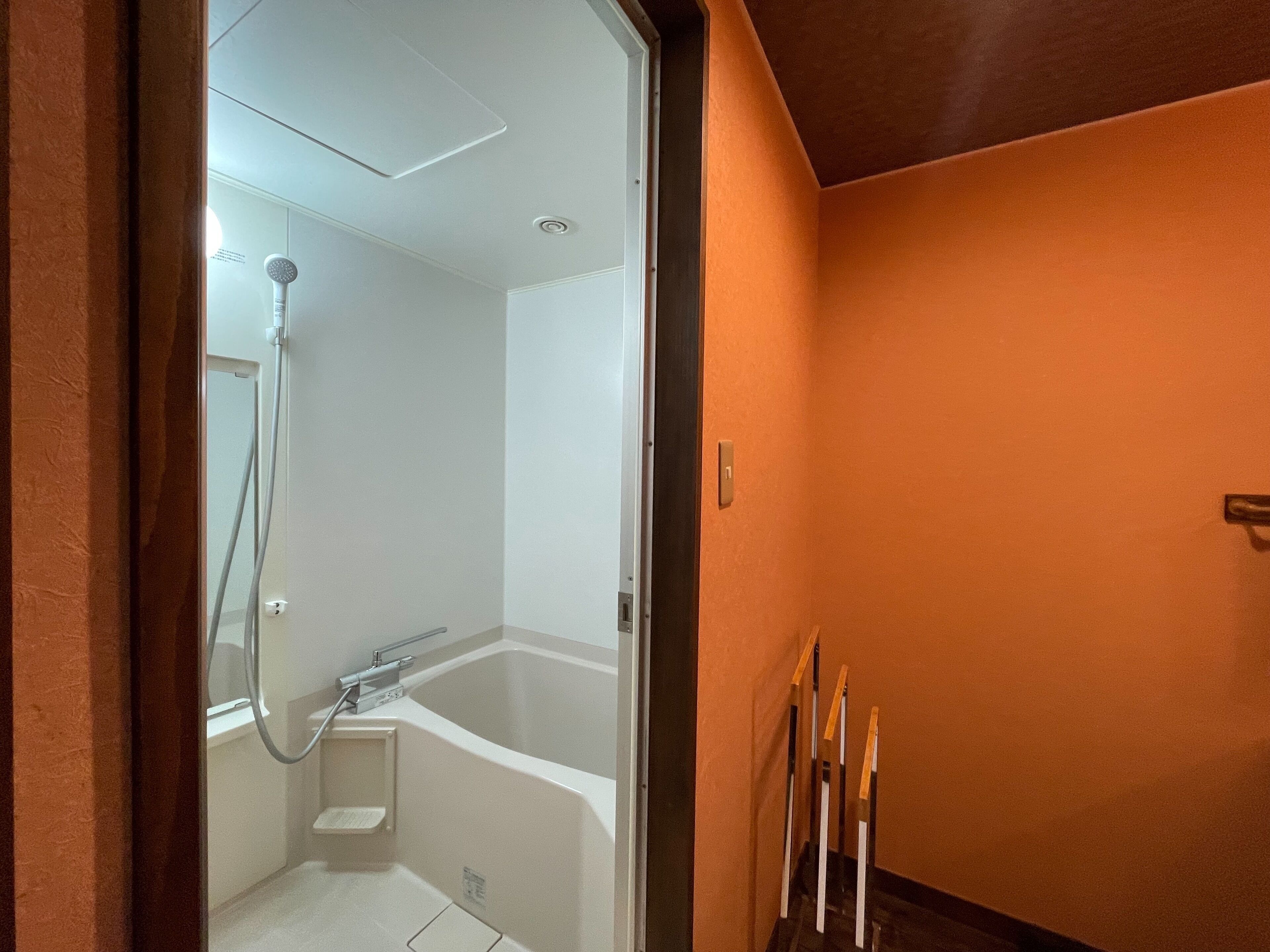 A bathroom with a bathtub, shower, and a small step stool.