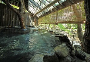 A traditional wooden bathhouse with a clear water pool, bamboo blinds, and a natural stone setting. - Kutsurogijuku Shintaki (Aizuwakamatsu)