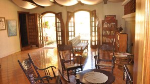 A spacious room with a tiled floor, wooden furniture, and a large window with a view of the outdoors. - Casa Inti (Managua)
