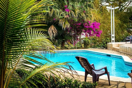 Una piscina al aire libre, sillones reclinables de piscina