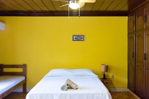 A room with a bed, a bench, a ceiling fan, a wall-mounted lamp, and a wardrobe. - Casa Inti (Managua)