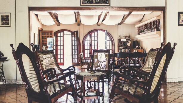 A traditional room with wooden rocking chairs, a central table, and a bookshelf. - Casa Inti (Managua)