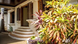 A building with a staircase leading to a door, surrounded by various plants. - Casa Inti (Managua)