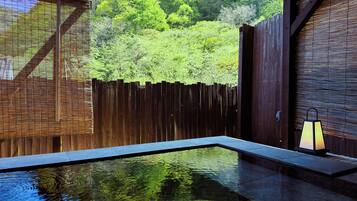 A clear pool with a wooden deck, surrounded by a wooden fence and lush greenery.