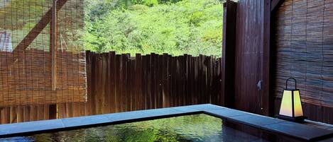 A clear pool with a wooden deck, surrounded by a wooden fence and lush greenery.