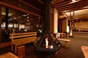 Un espace extérieur accueillant, aménagé avec des bancs en bois et doté d’un foyer central.