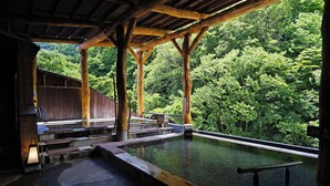 Un bain traditionnel en bois, avec vue sur une colline boisée.