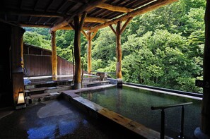 A traditional wooden bathhouse with a view of a forested hillside. - Yuze Hotel (Kazuno)