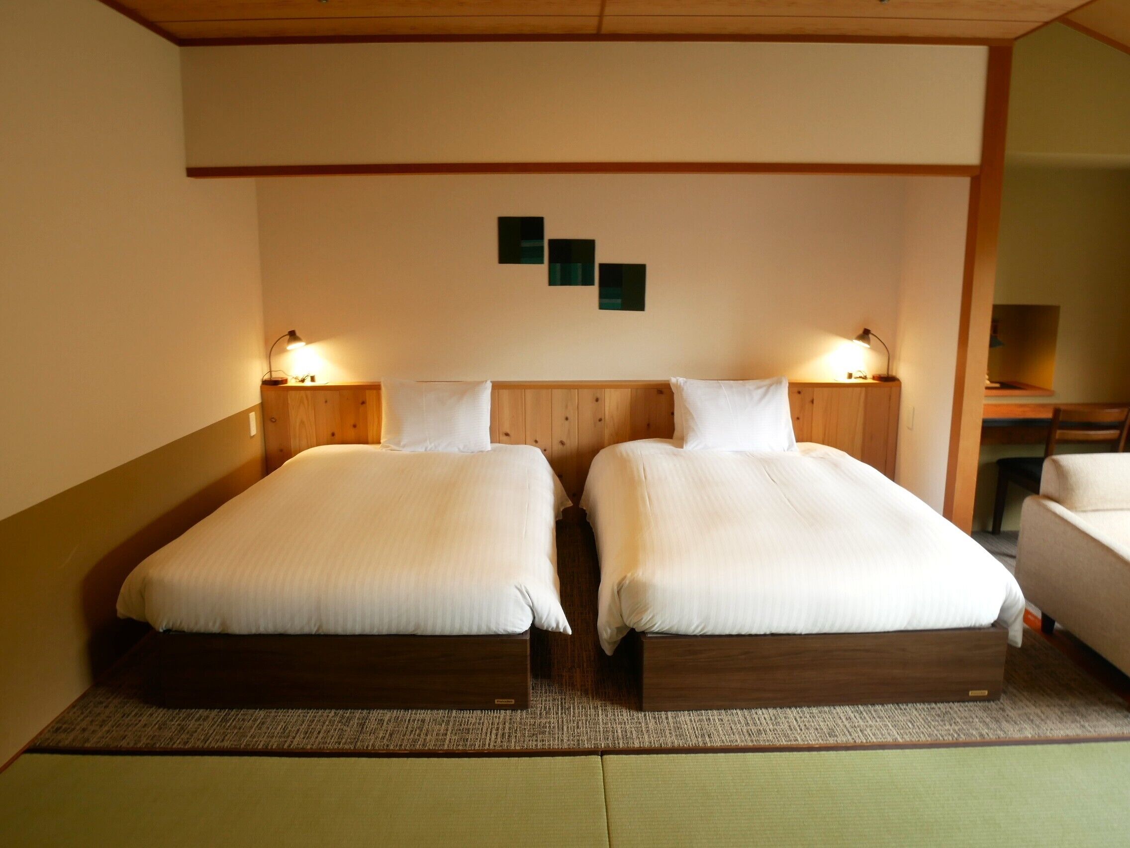 Een hotelkamer met twee bedden, houten hoofdeinden en bedlampjes.