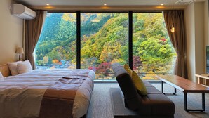 Une chambre d’hôtel avec un grand lit, un canapé et une vue sur une montagne boisée.