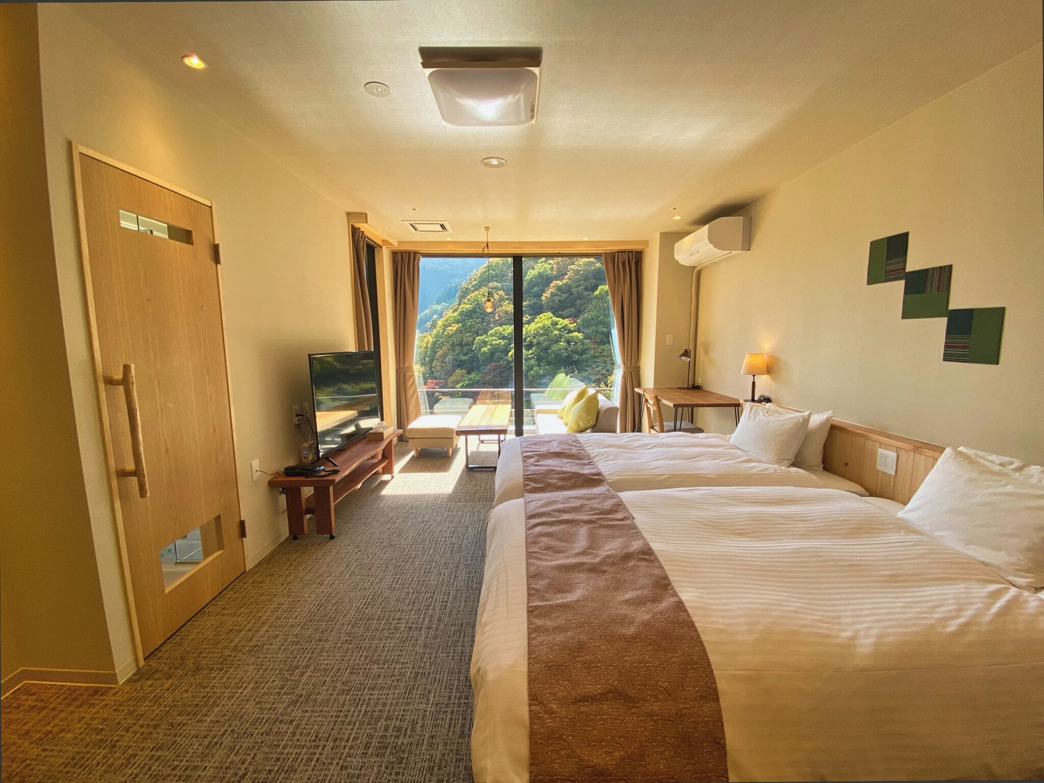 Una habitación de hotel con una cama grande, televisión, escritorio y vistas a un área boscosa.