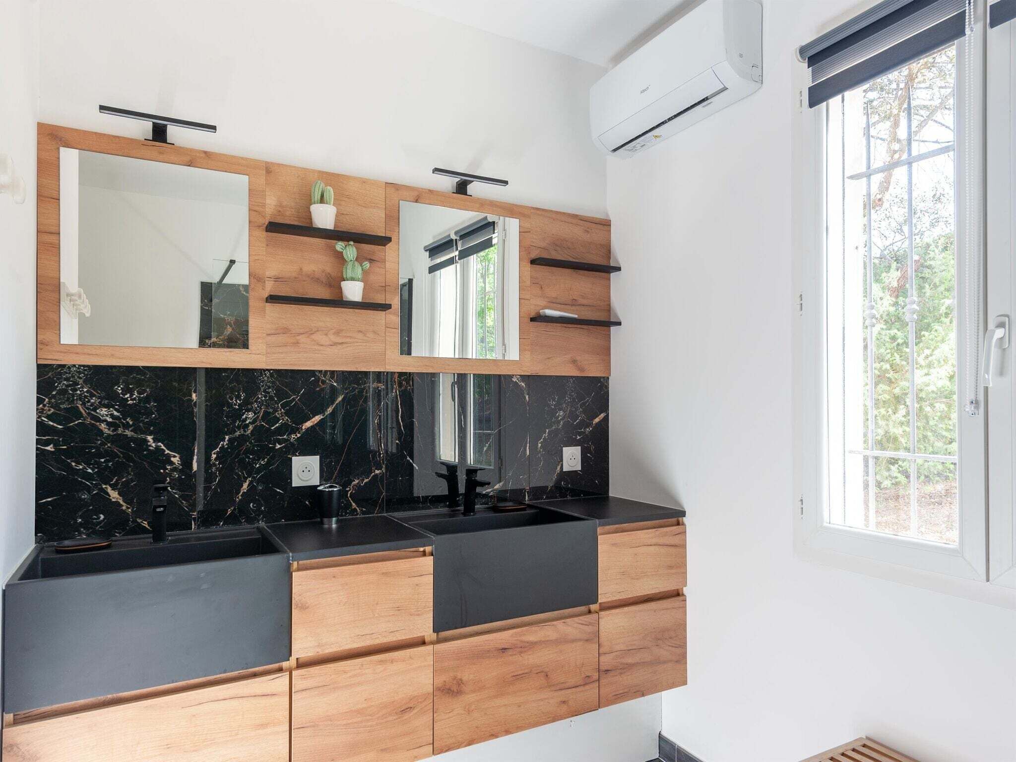 Ein modernes Badezimmer mit zwei Waschbecken, einem großen Spiegel und einem Fenster.